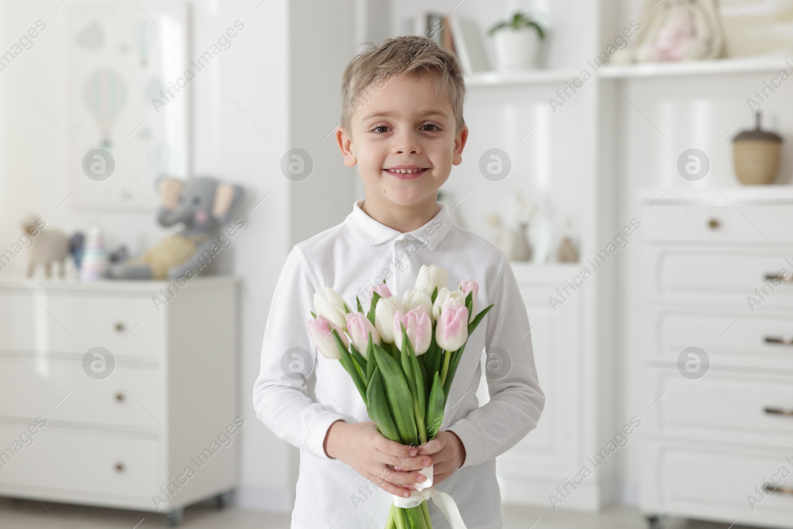 Photo of Cute little boy with bouquet of tulips at home