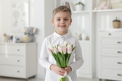 Cute little boy with bouquet of tulips at home