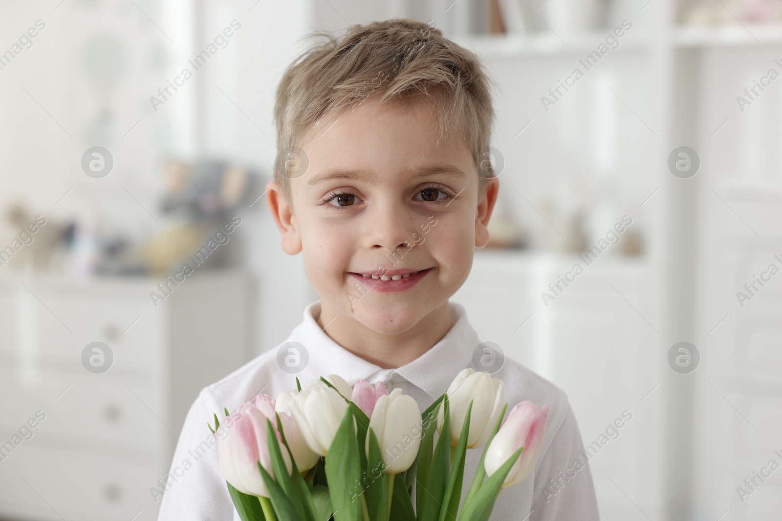 Photo of Cute little boy with bouquet of tulips at home