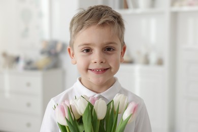 Cute little boy with bouquet of tulips at home