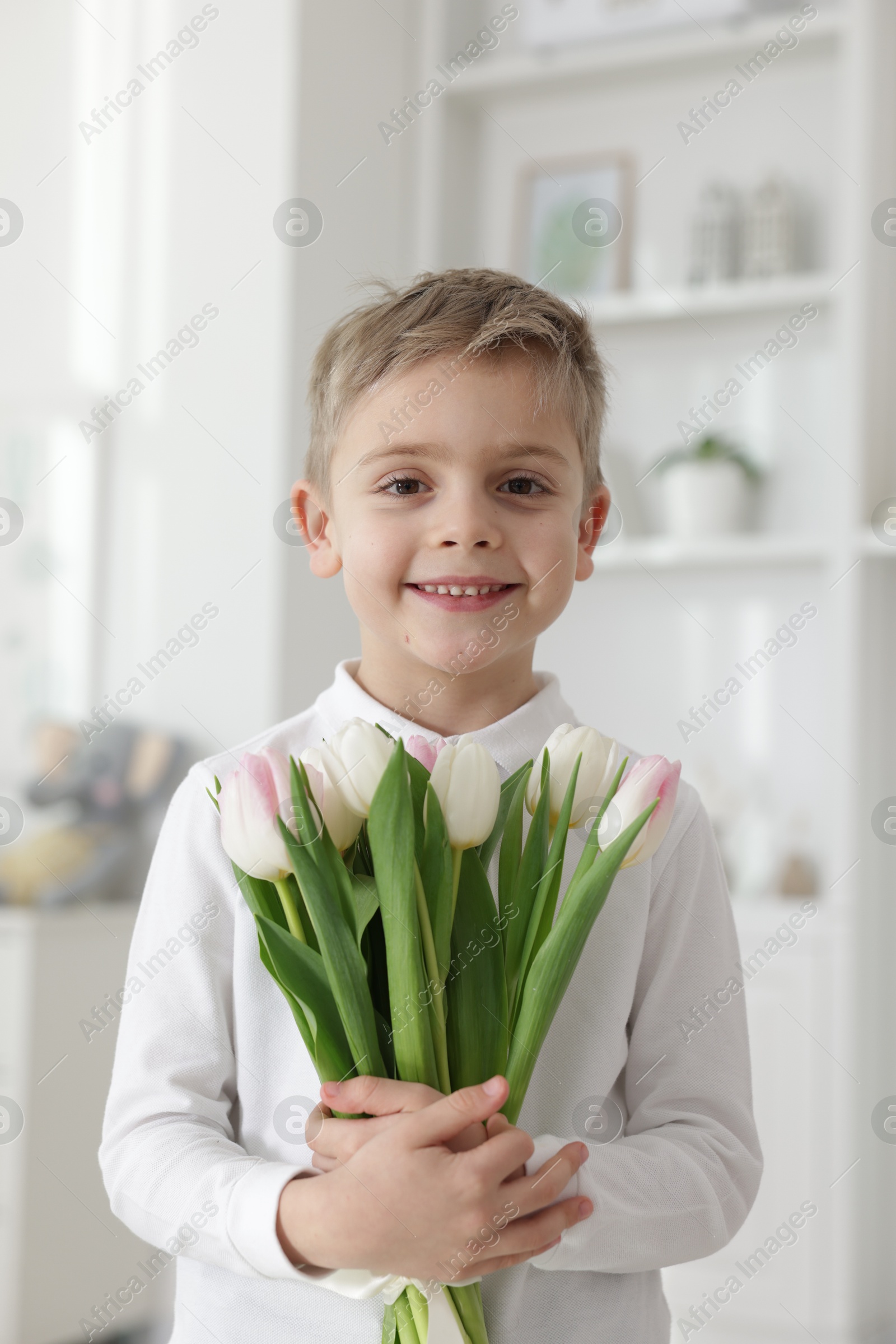 Photo of Cute little boy with bouquet of tulips at home