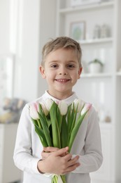 Cute little boy with bouquet of tulips at home