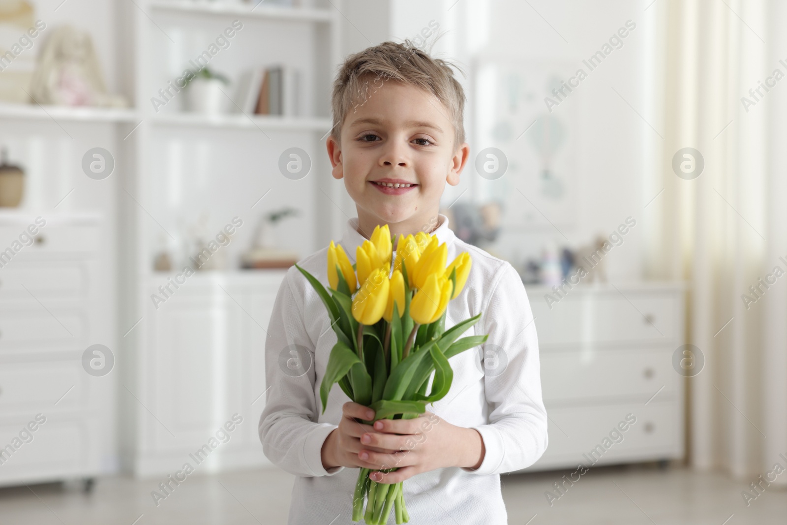 Photo of Cute little boy with bouquet of tulips at home