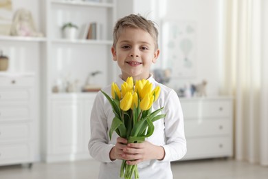 Cute little boy with bouquet of tulips at home