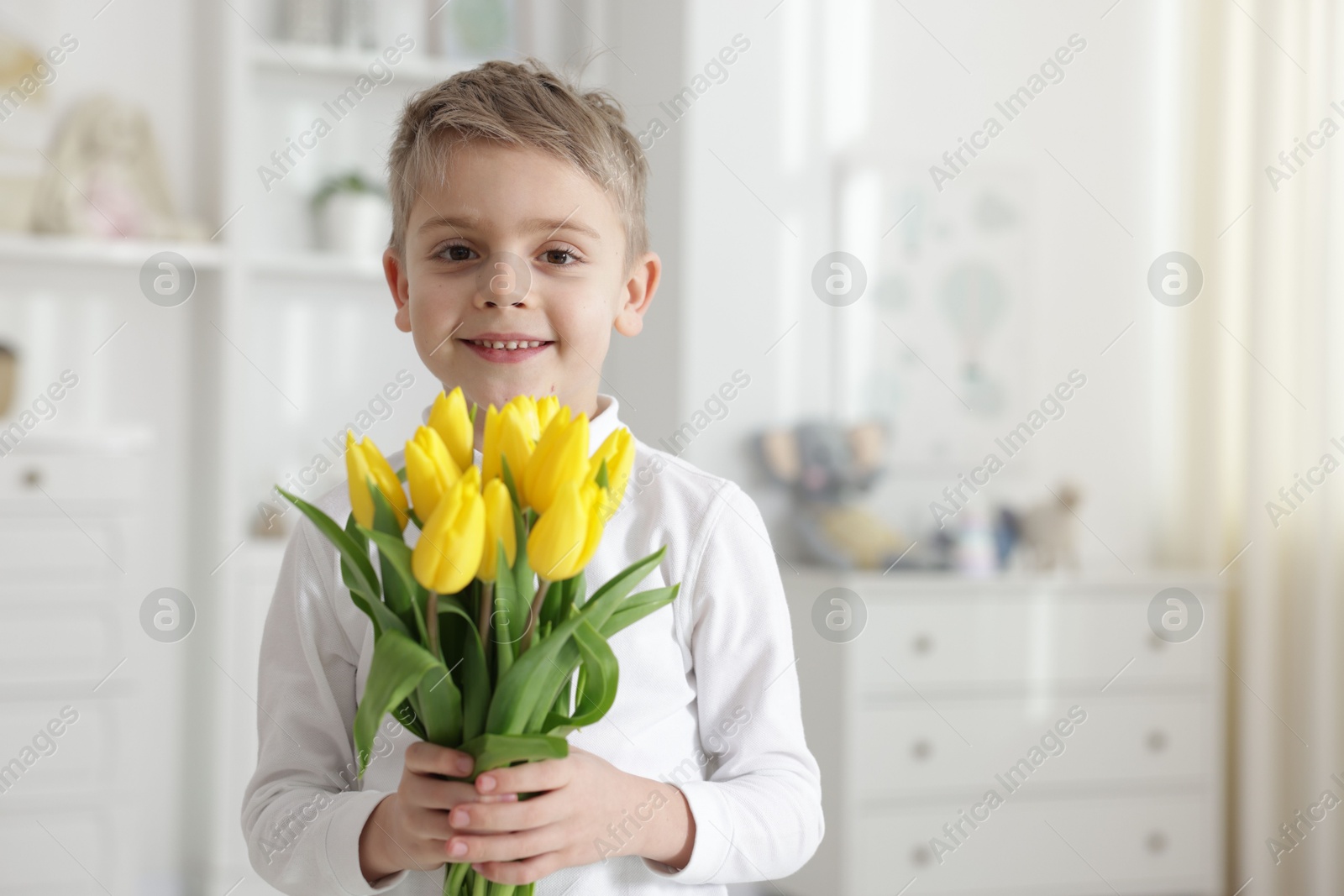 Photo of Cute little boy with bouquet of tulips at home. Space for text