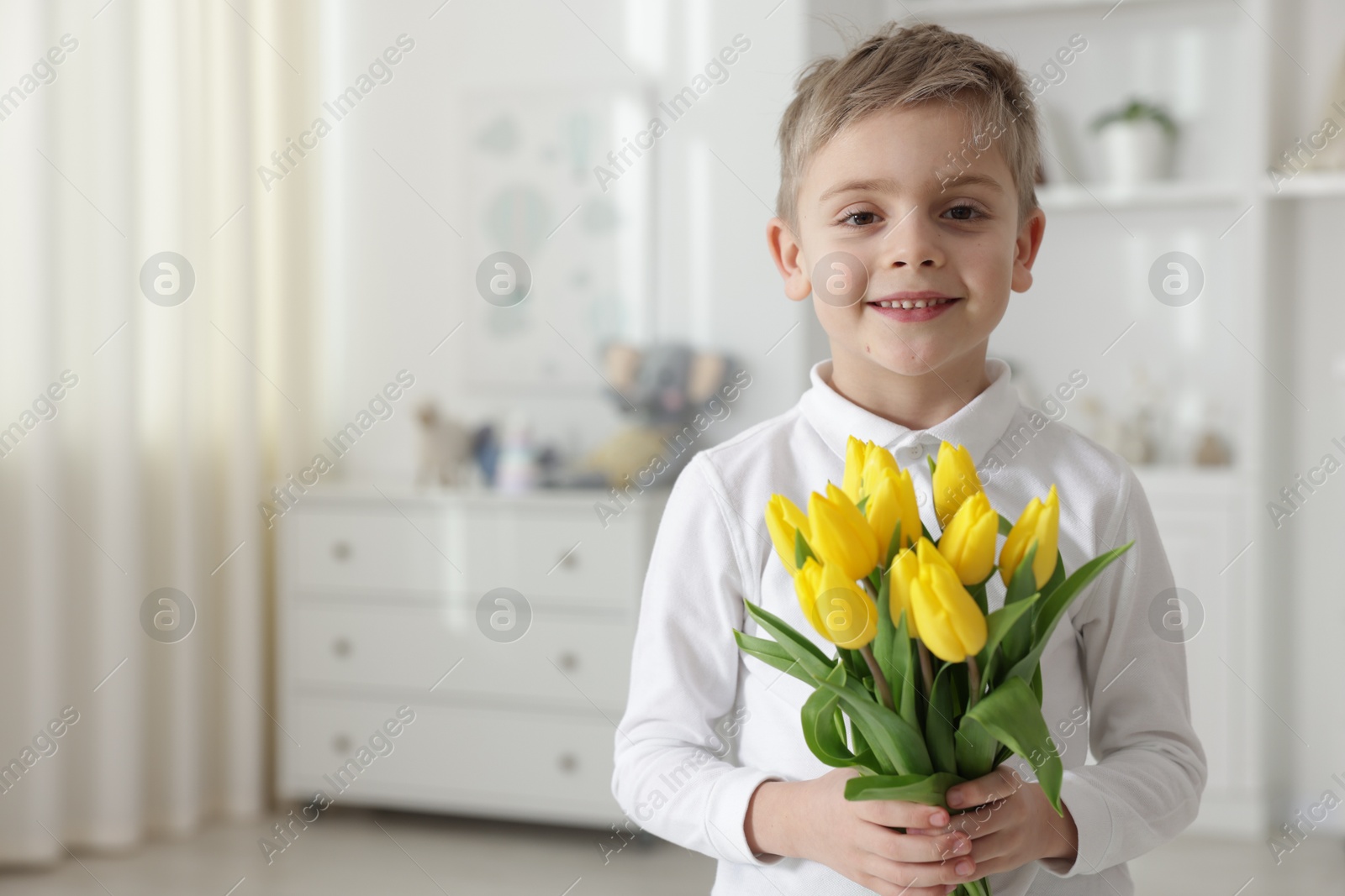 Photo of Cute little boy with bouquet of tulips at home. Space for text