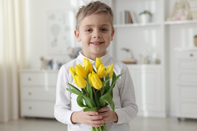 Photo of Cute little boy with bouquet of tulips at home