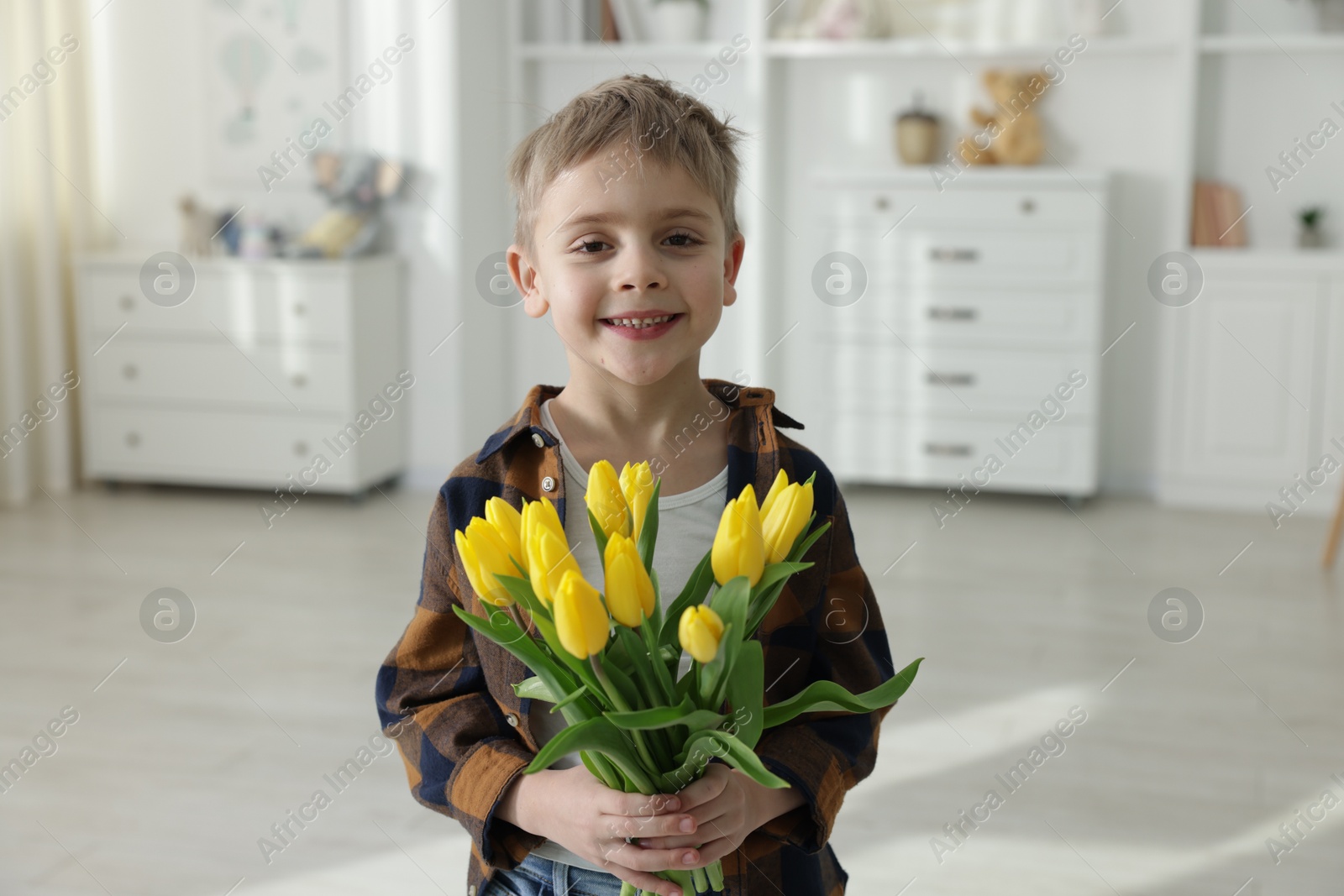 Photo of Cute little boy with bouquet of tulips at home