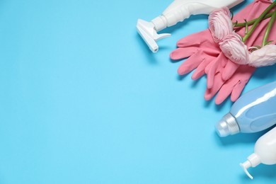 Photo of Spring cleaning. Detergents, gloves and flowers on light blue background, flat lay. Space for text