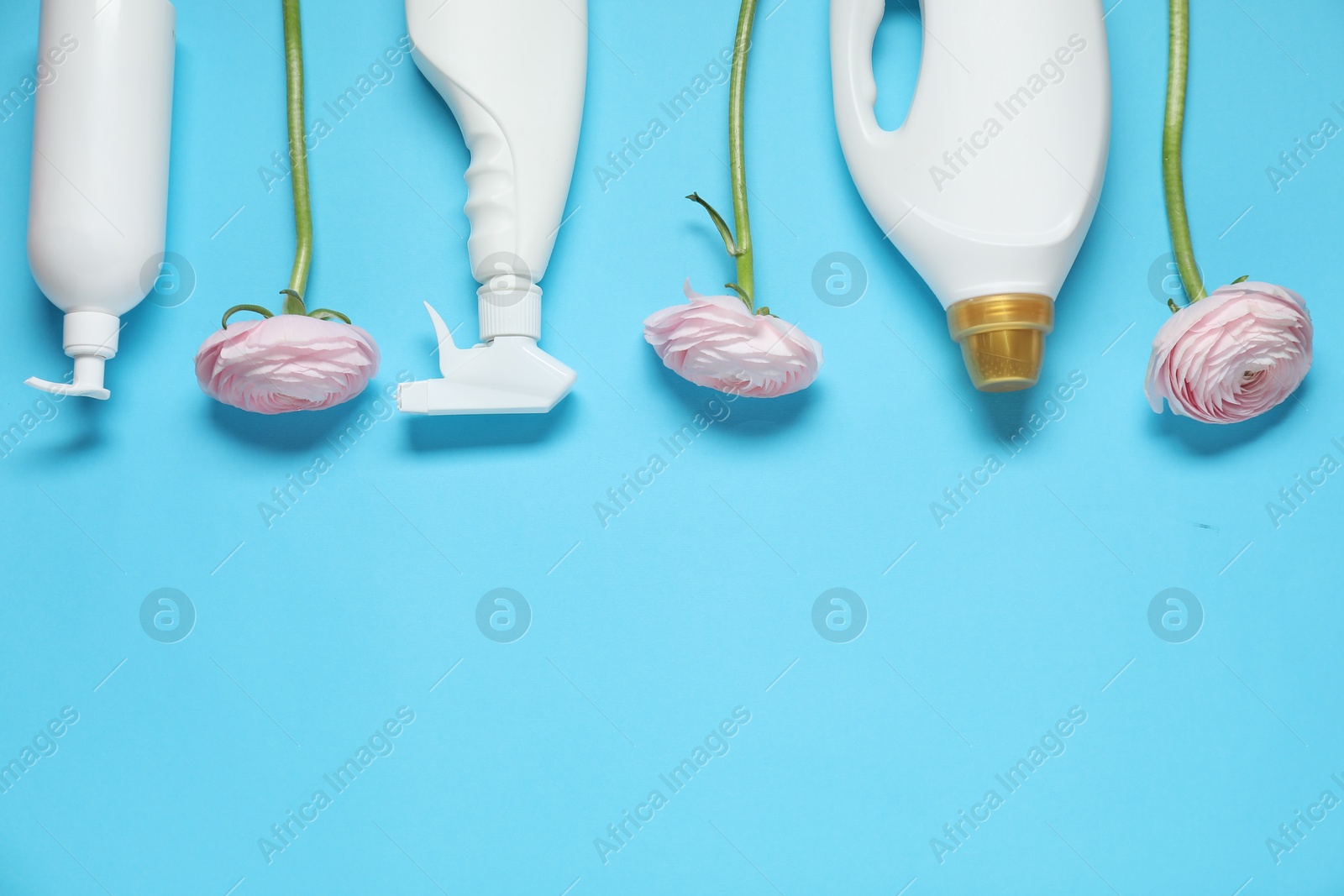 Photo of Spring cleaning. Detergents and flowers on light blue background, flat lay. Space for text