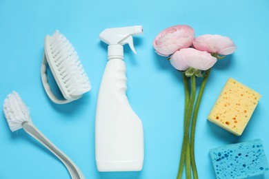 Photo of Spring cleaning. Detergent, supplies and flowers on light blue background, flat lay