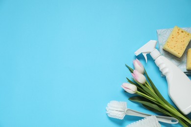 Photo of Spring cleaning. Detergent, supplies and tulips on light blue background, flat lay. Space for text