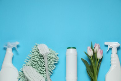 Photo of Spring cleaning. Detergents, supplies and tulips on light blue background, flat lay. Space for text