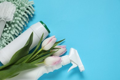 Photo of Spring cleaning. Detergents, supplies and tulips on light blue background, flat lay. Space for text