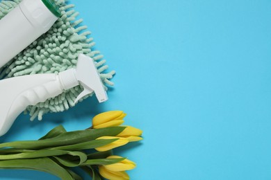 Photo of Spring cleaning. Detergents, supplies and tulips on light blue background, flat lay. Space for text