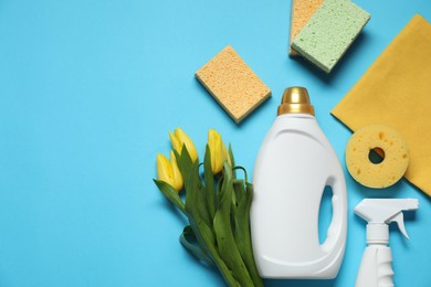 Photo of Spring cleaning. Detergents, supplies and tulips on light blue background, flat lay. Space for text