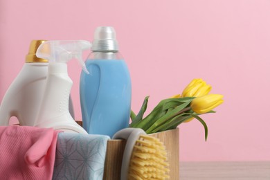 Photo of Spring cleaning. Detergents, supplies and tulips on table against pink background, closeup