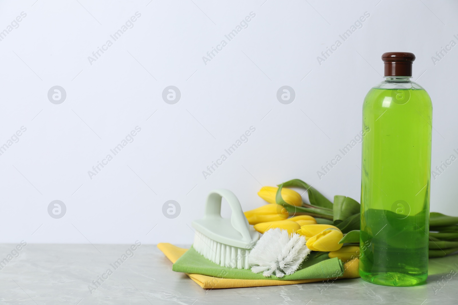 Photo of Spring cleaning. Detergent, supplies and tulips on light grey table against white background, space for text