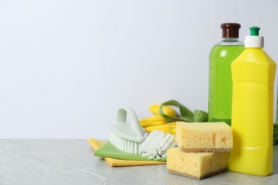 Photo of Spring cleaning. Detergents, supplies and tulips on light grey table against white background, space for text