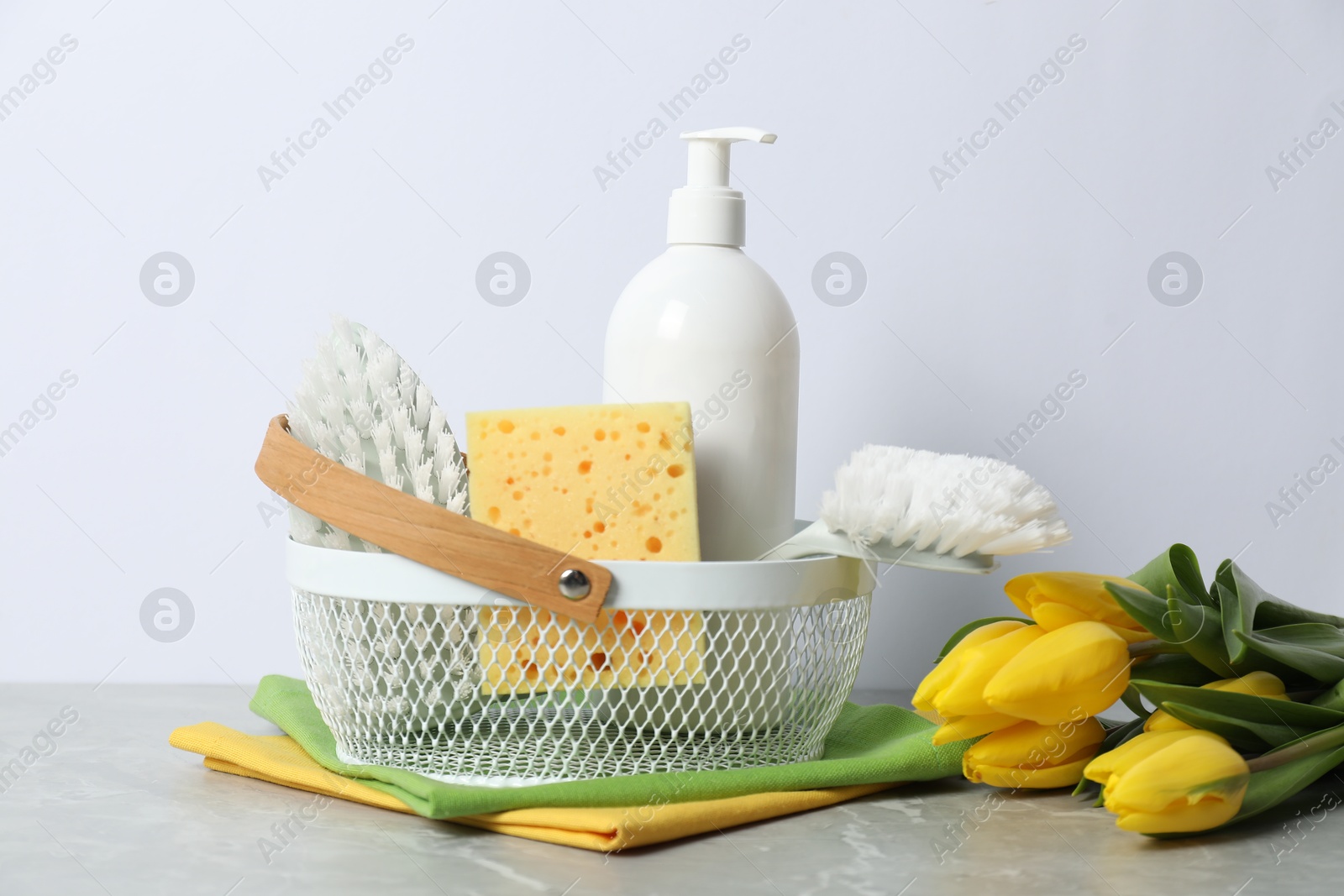 Photo of Spring cleaning. Detergent, supplies and tulips on light grey table against white background