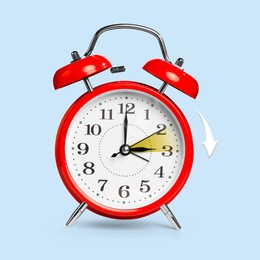 Daylight saving time. Red alarm clock on light blue background. Highlighted area and arrow showing time change by one hour forward