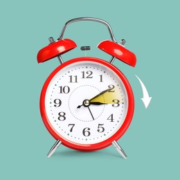 Image of Daylight saving time. Red alarm clock on pale turquoise background. Highlighted area and arrow showing time change by one hour forward