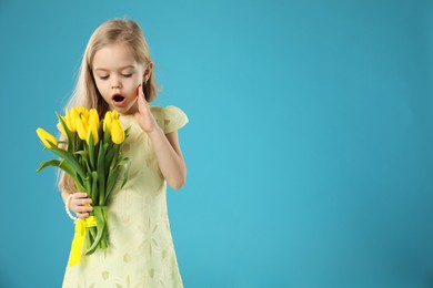 Photo of Cute little girl with beautiful yellow tulips on light blue background, space for text. Spring season