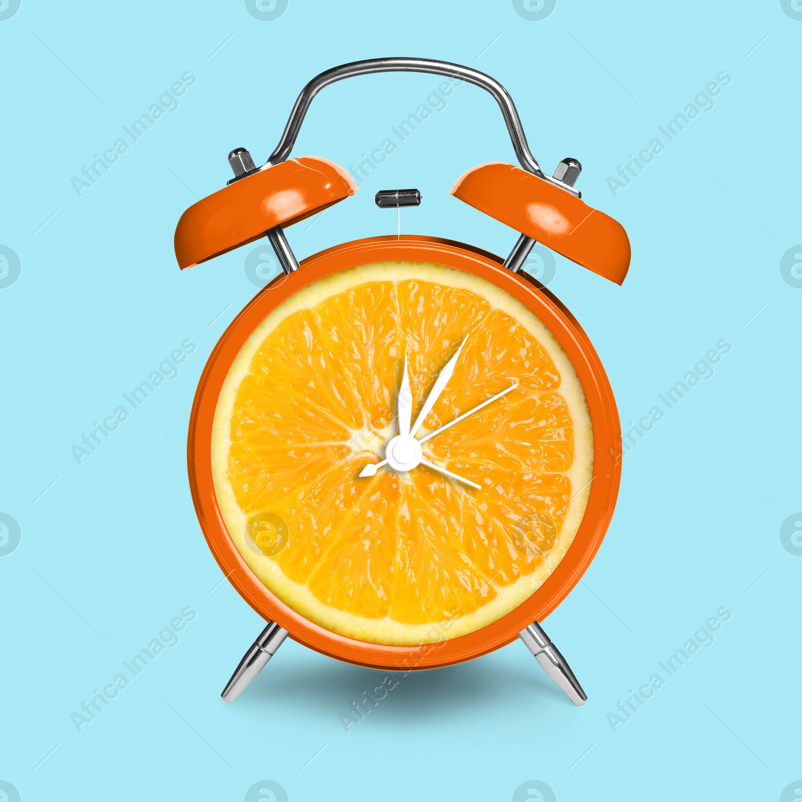 Image of Alarm clock with sliced orange instead of dial on light blue background