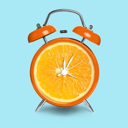 Image of Alarm clock with sliced orange instead of dial on light blue background