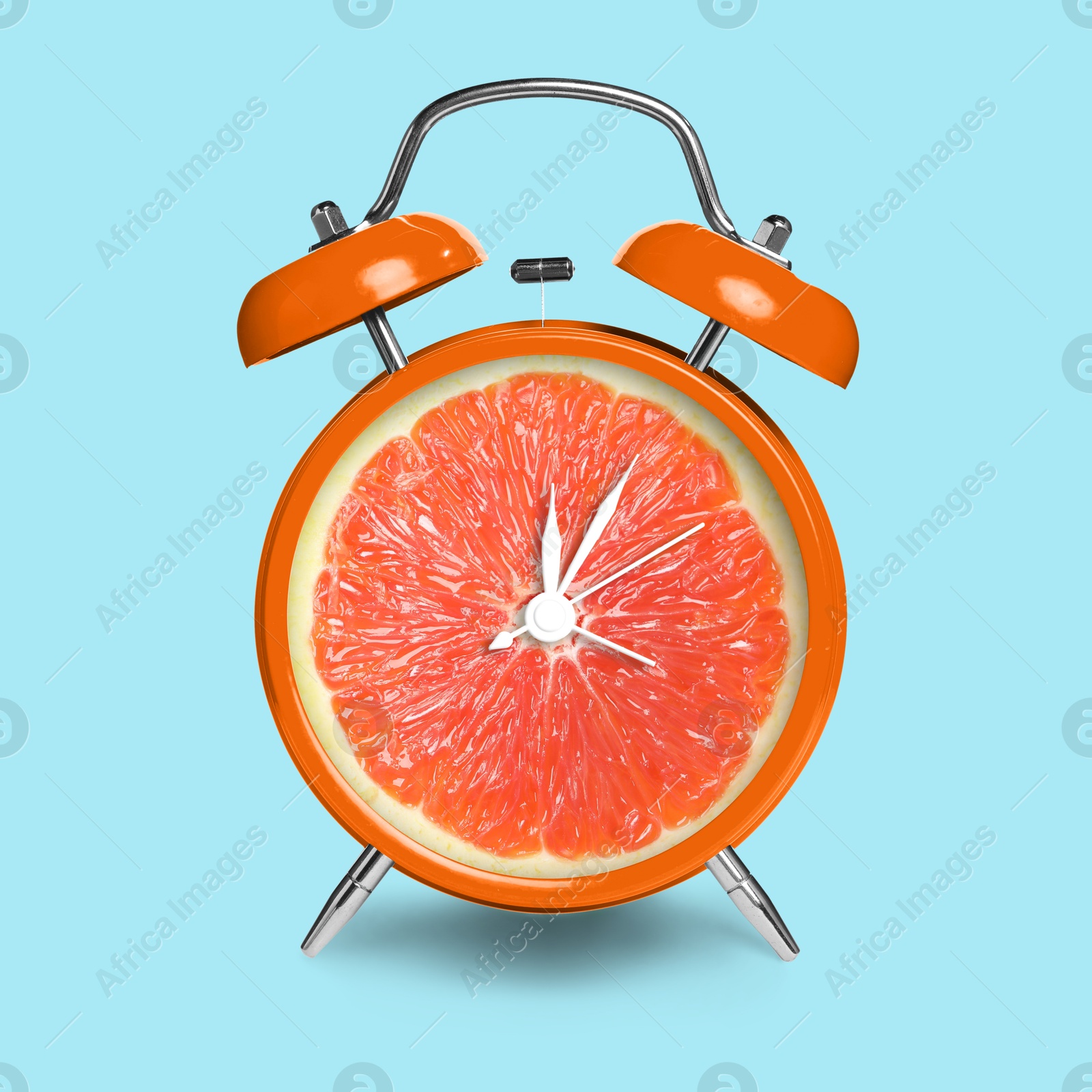 Image of Alarm clock with sliced orange instead of dial on light blue background