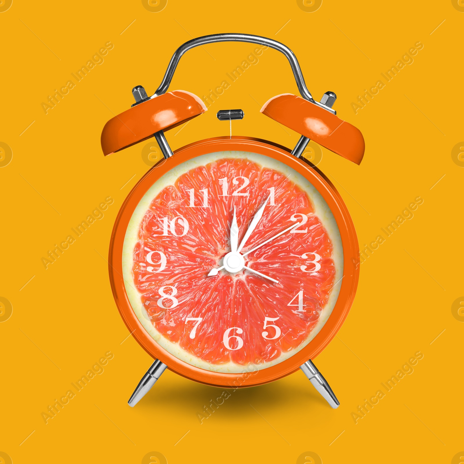 Image of Alarm clock with sliced orange instead of dial on orange background