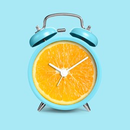 Image of Alarm clock with sliced orange instead of dial on light blue background