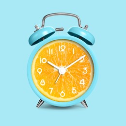 Image of Alarm clock with sliced orange instead of dial on light blue background