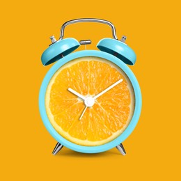 Image of Alarm clock with sliced orange instead of dial on orange background