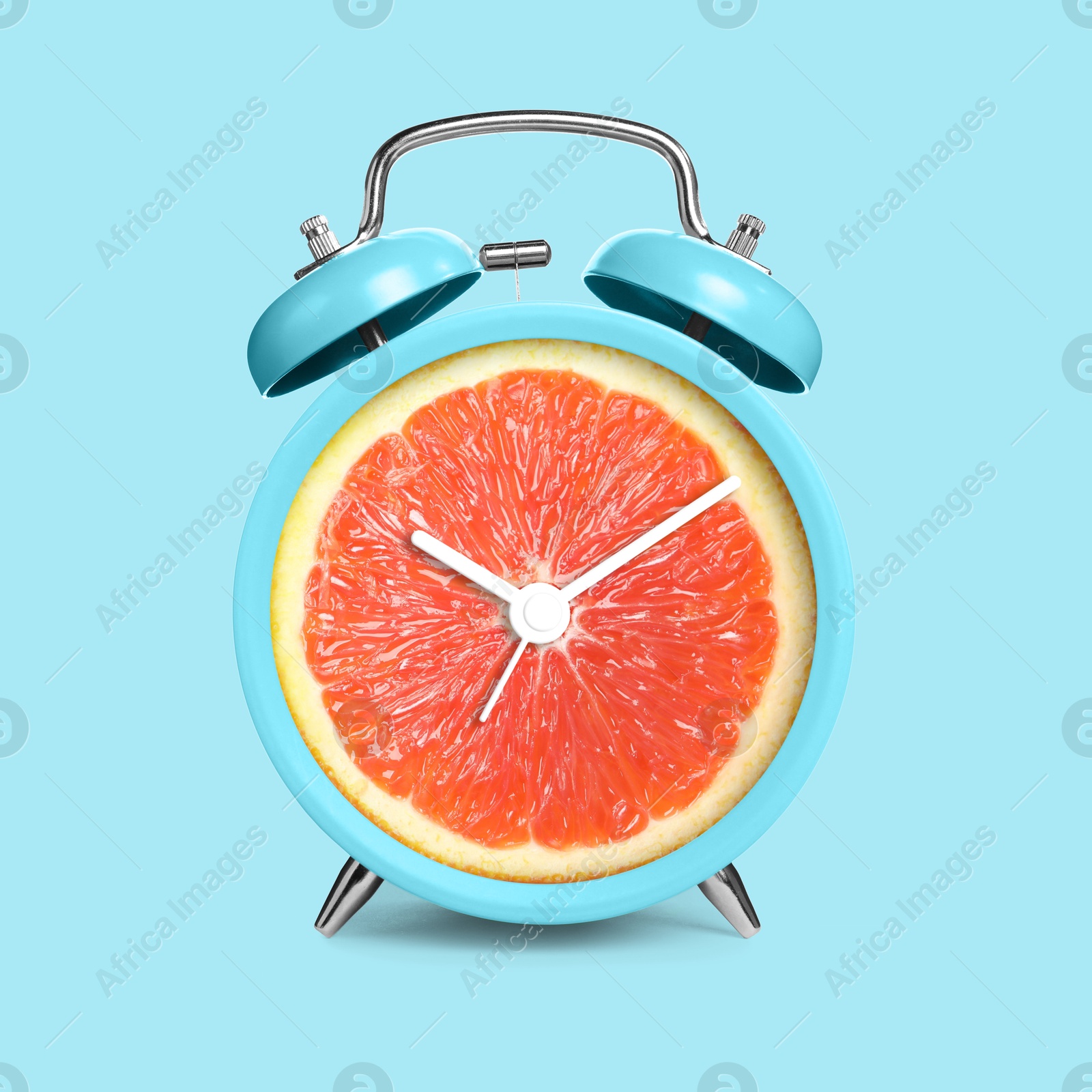 Image of Alarm clock with sliced orange instead of dial on light blue background