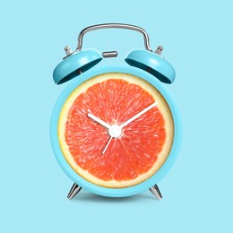 Image of Alarm clock with sliced orange instead of dial on light blue background