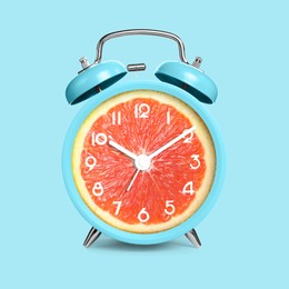 Image of Alarm clock with sliced orange instead of dial on light blue background