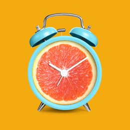 Image of Alarm clock with sliced orange instead of dial on orange background