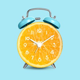 Image of Alarm clock with sliced orange instead of dial on light blue background