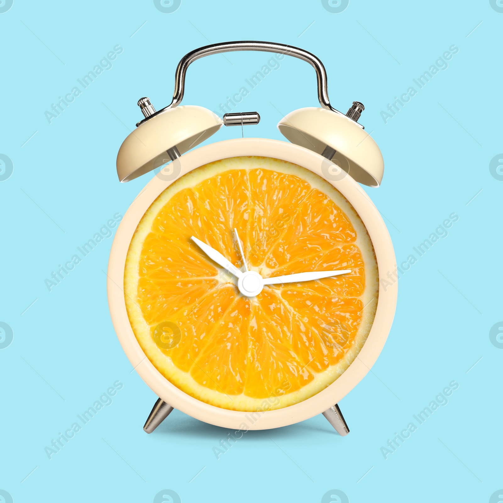 Image of Alarm clock with sliced orange instead of dial on light blue background