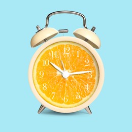 Image of Alarm clock with sliced orange instead of dial on light blue background