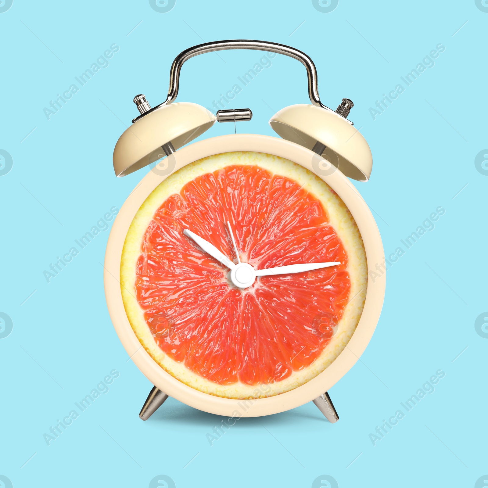 Image of Alarm clock with sliced orange instead of dial on light blue background