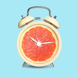 Image of Alarm clock with sliced orange instead of dial on light blue background