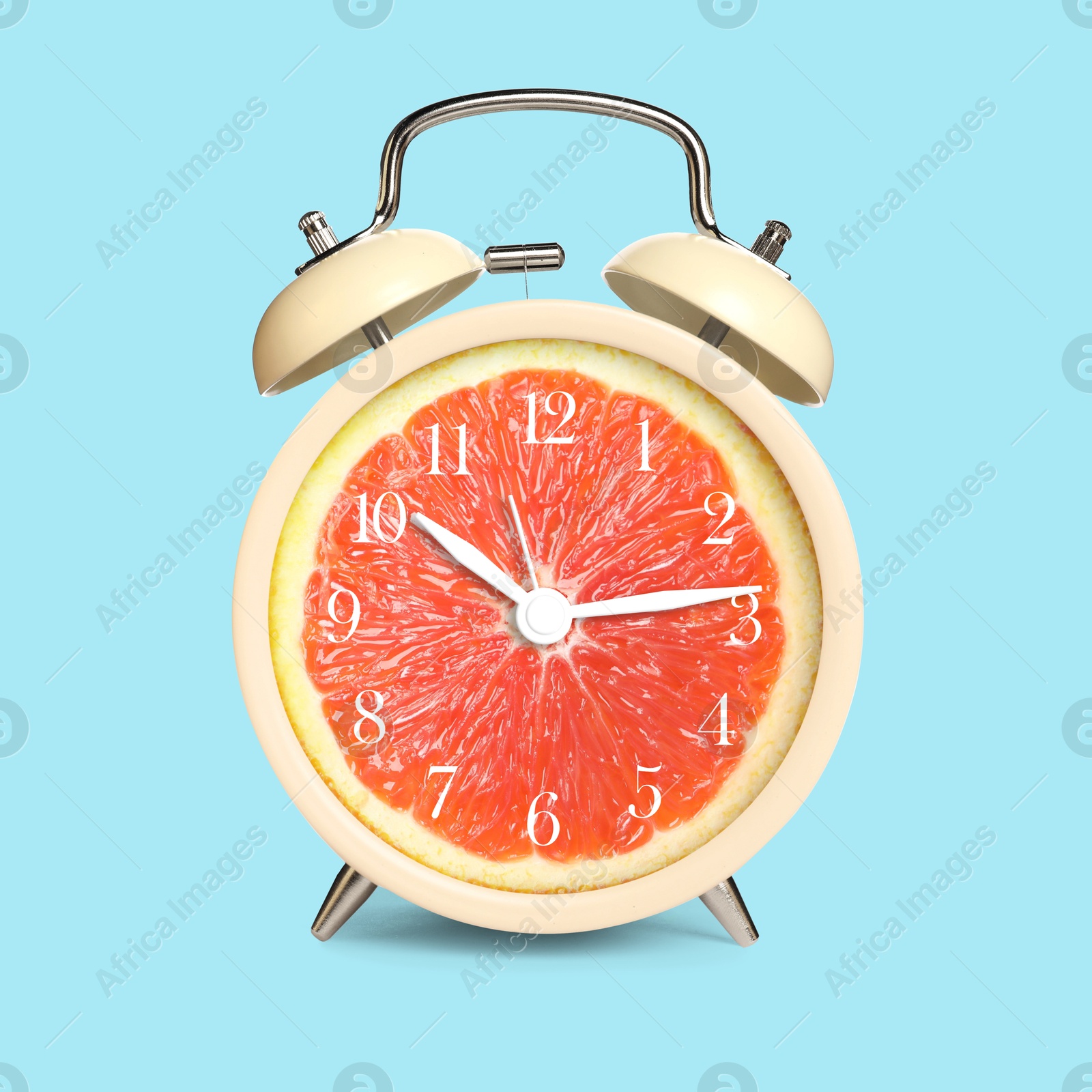 Image of Alarm clock with sliced orange instead of dial on light blue background