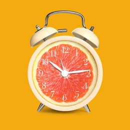 Image of Alarm clock with sliced orange instead of dial on orange background