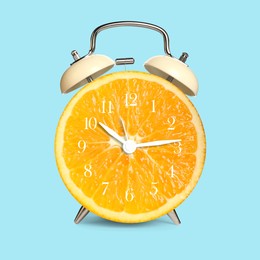 Image of Alarm clock with sliced orange instead of dial on light blue background