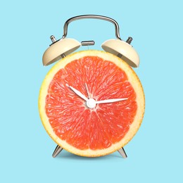 Image of Alarm clock with sliced orange instead of dial on light blue background