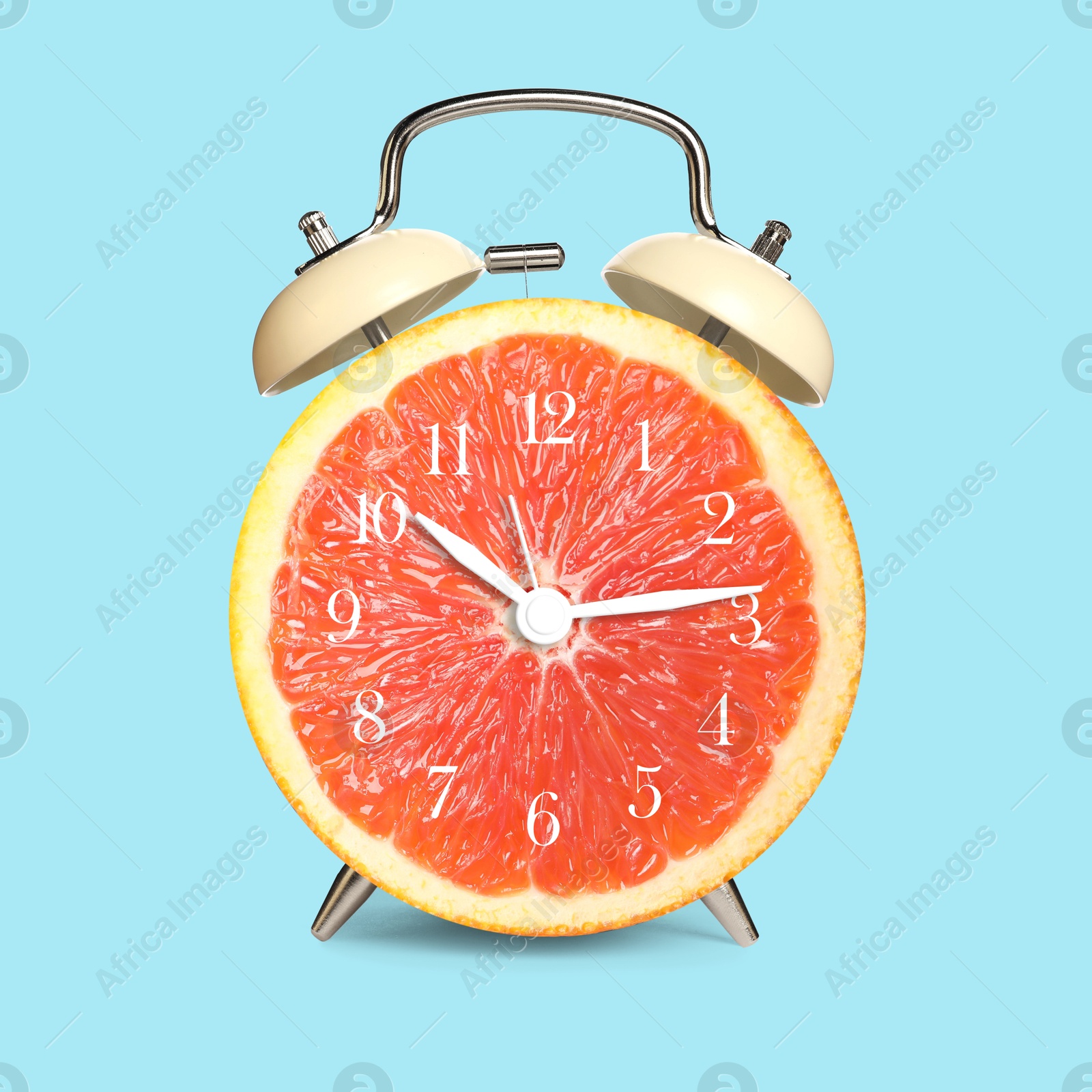 Image of Alarm clock with sliced orange instead of dial on light blue background