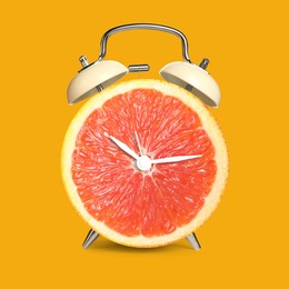 Image of Alarm clock with sliced orange instead of dial on orange background