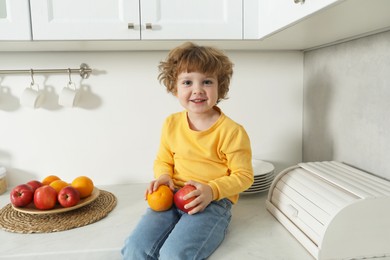 Little boy with fruits on countertop in kitchen